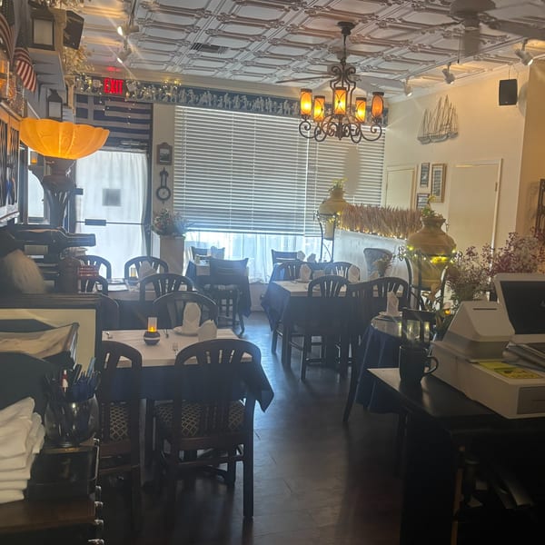 Interior of Stella's Greek Cuisine, featuring dining tables, Greek flags, and decorative elements.