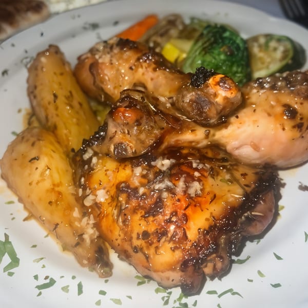 Greek roasted chicken with potatoes and vegetables, garnished with herbs and coarse salt.
