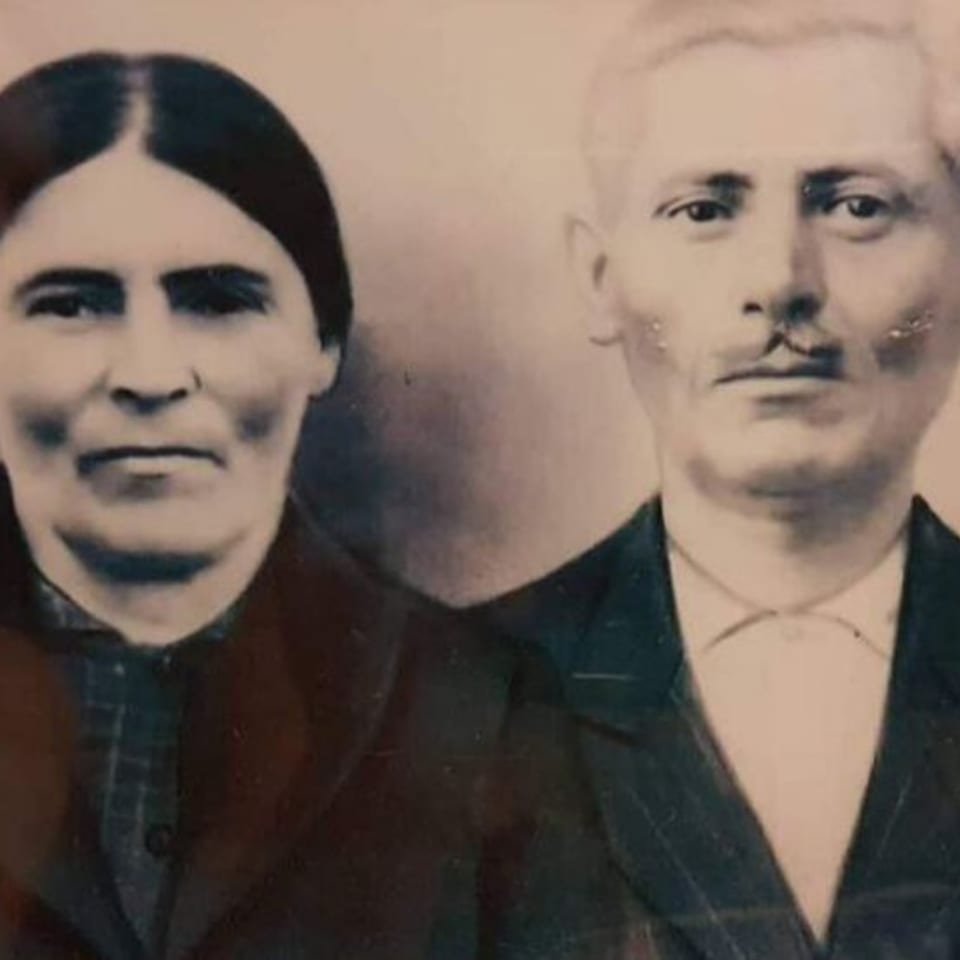 Sepia-toned portrait of a stern-looking woman and a man with a mustache, likely Stella's ancestors.
